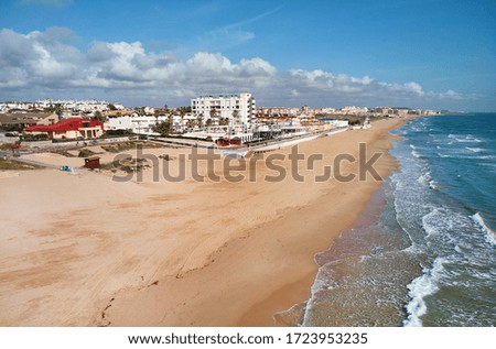 Aerial photography empty sandy coastline of Costa Blanca at sunny day. Mediterranean Sea surf water blue cloudy sky, picturesque scenery, due coronavirus all beaches are closed, nobody. Spain. España
