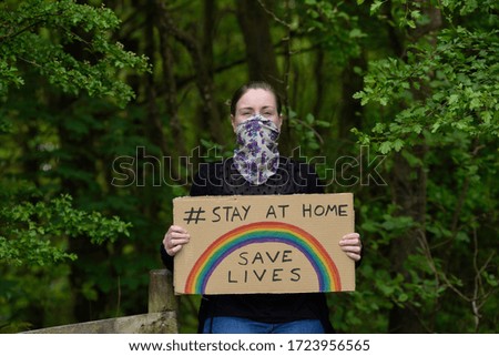 Young women holding a cardboard placard stay at home save lives during coronavirus pandemic.