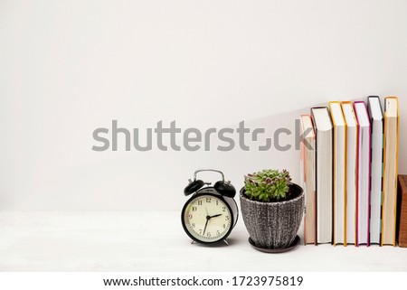 Copy space. Workplace office worker with accessories and white desk. An alarm clock, a succulent in a ceramic pot and a stack of books on a student's desk.