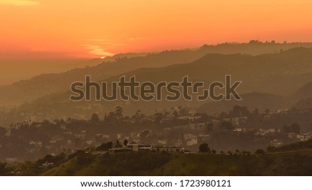 Sunset over the Hollywood Hills, Los Angeles. The sky is various shades of orange and yellow.