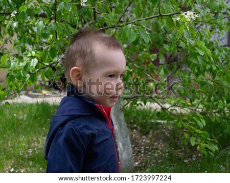 Childhood. Rest outside the city. The child walks in the garden against the backdrop of greenery, natural background. Spring, portrait of a child on a green background.