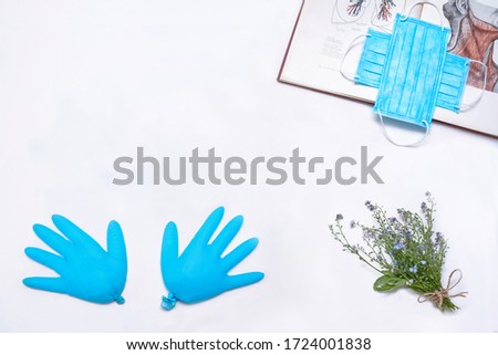 Blue disposable medical mask and latex gloves. Anatomy Medical Reference on a white background with forget-me-nots. Coronavirus pandemic.  medical mask for protection against flu diseases. COVID-19. 