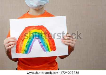 Little Caucasian Girl Holding Painted Rainbow During Covid-19 Quarantine As a Sign Of Hope. Stay At Home Social Media Campaign For Coronavirus Prevention