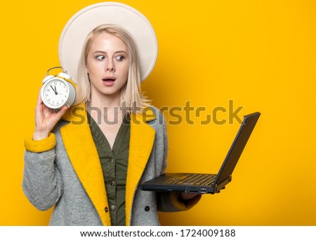 Style blonde woman in hat nad autumn season coat with notebook on yellow background