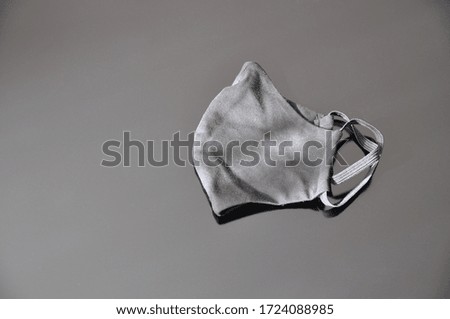 A black sanitary mask used to prevent COVID-19 or coronavirus. Black medical mask on a black background