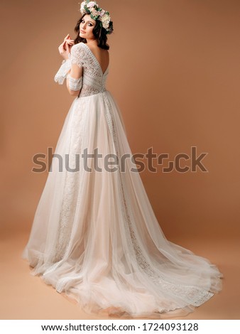 Wedding gown in bohemian style. Studio portrait of beautiful bride in gorgeous wedding dress with long subtle train. 
