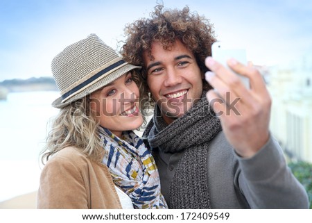 Cheerful couple taking picture with smartphone
