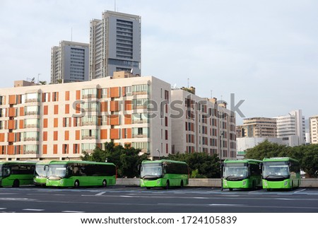 green buses at a bus station in the background of a residential city
