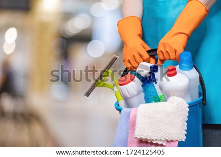 A bucket of cleaning products in hands with rubber gloves on a blurred background. Royalty-Free Stock Photo #1724125405