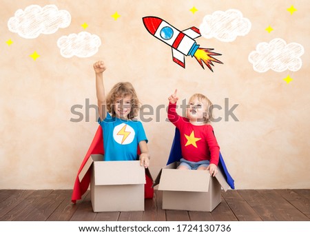 Superheroes children playing in cardboard box. Kids having fun at home. Childhood dream and imagination concept