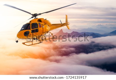 Yellow Helicopter flying over the Rocky Mountains during a sunny sunset. Aerial Landscape from British Columbia, Canada near Vancouver. Composite Royalty-Free Stock Photo #1724135917