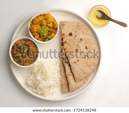 Veg Thali or Vegetarian Indian food plate with roti or flat bread, ghee butter, rice, cauliflower curry and daal or lentil Royalty-Free Stock Photo #1724138248