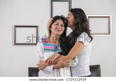 Mexican mother and daughter hugging and kissing on mother's day 
