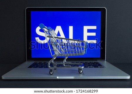 Metal shopping basket on the computer and the inscription on the screen - sale on a bright blue background. The concept of online shopping