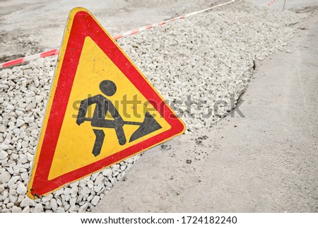 Warning sign road works for repair, man with a shovel. They blocked the road because repair work is underway.