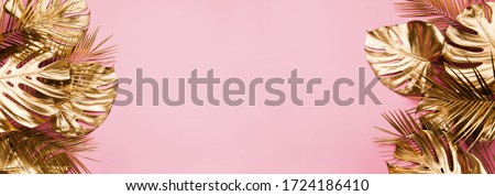 Gold painted tropical date palm and monstera leaves border frame on pastel pink abstract background isolated. Room for text. Beauty fashion banner template. Royalty-Free Stock Photo #1724186410