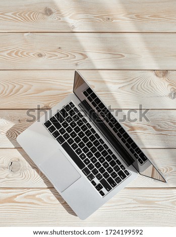 Top view of laptop on loft-style table in sunny day. Coworking or working at home concept image.