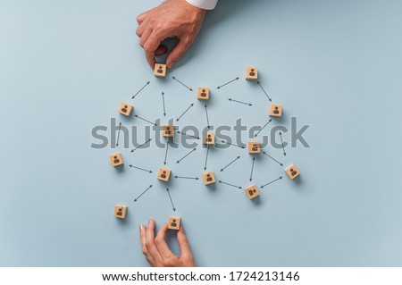 Social distancing conceptual image - male and female hands placing wooden blocks with person icon on them in a recommended distance between them.  Royalty-Free Stock Photo #1724213146