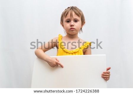Little girl is pointing on  a sheet of white paper in her hands on a white background. There is abrasion on the face of the child. Domestic Violence Photos. European appearance, 4 years
