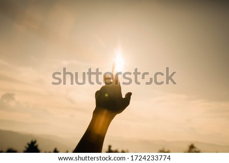 Closeup silhouette hand with sunrise. Woman hands holding the sun at dawn. Freedom and spirituality concept.