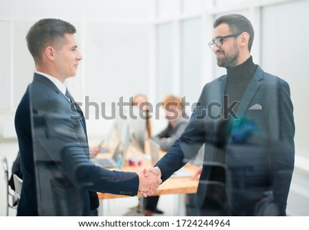 through the glass. business partners handshake in the office