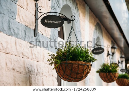 pot flowers hanging over the door with a sign that says "welcome".