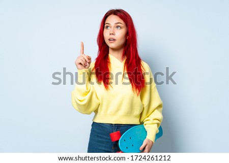 Teenager skater girl isolated on white background thinking an idea pointing the finger up