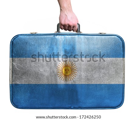 Tourist hand holding vintage leather travel bag with flag of Argentina