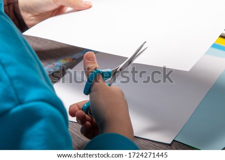 teenager's hands are cutting paper with scissors. making origami