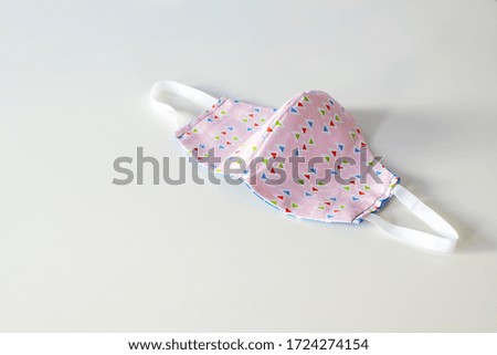 Homemade community face mask sewn from cotton as protection against coronavirus pandemic on a gray background, copy space, selected focus, narrow depth of field