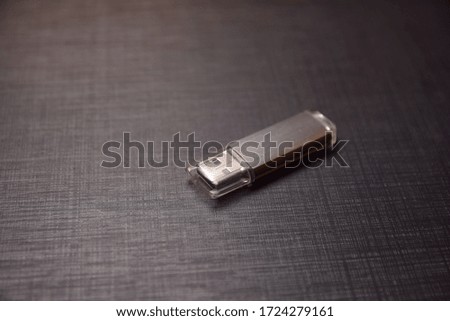 The gray flash drive lies on a dark background