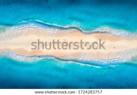 Aerial view of transparent blue sea with waves on the both sides and people on sandy beach at sunset. Summer travel in Zanzibar, Africa. Tropical landscape with lagoon, white sand and ocean. Top view Royalty-Free Stock Photo #1724283757
