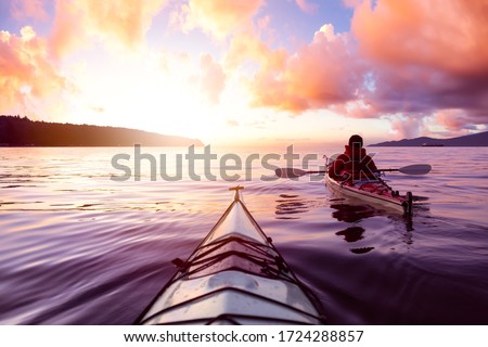 Adventurous Man Sea Kayaking in the Ocean during a colorful Sunset. Cloudy Sky Composite. Taken in Jericho, Vancouver, British Columbia, Canada. Royalty-Free Stock Photo #1724288857
