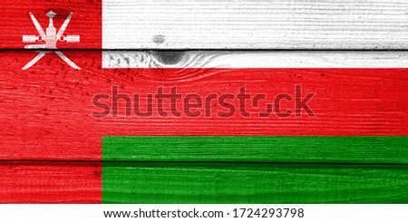 Oman flag painted on old wood plank background. Brushed natural light knotted wooden board texture. Wooden texture background flag of Oman