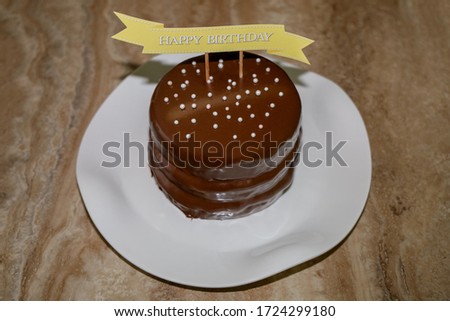 A cake with chocolate frosting and a happy birthday sign on top.