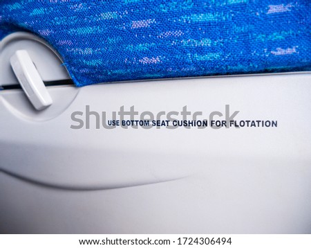 Use bottom seat cushion for flotation warning instruction text on aircraft seat. (Selective focus)