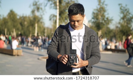Front portrait shot of a young Asian man taking a picture of Red Square in Moscow. Tourist Travel concept.