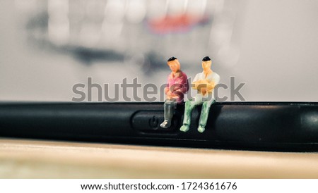 Miniature people sitting on the smartphone with copy space