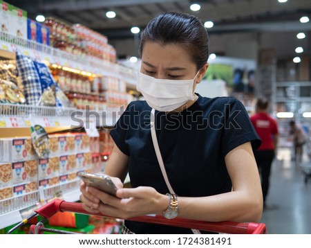 Woman wearing disposable protective face mask shopping in supermarket during coronavirus pneumonia outbreak and lockdown
