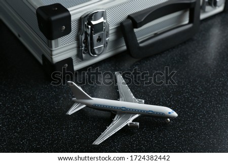 travel concept. Conceptual photo of a tourist trip. toy airplane and suit case on a black background.