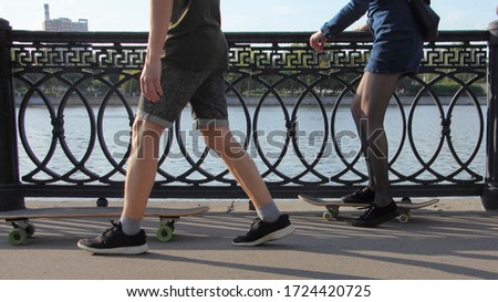 A guy teaches a girl to ride a skateboards without safety equipment kneepads in a Park on a Sunny summer day, Moscow outdoor activity vacation, waist-high side view close up