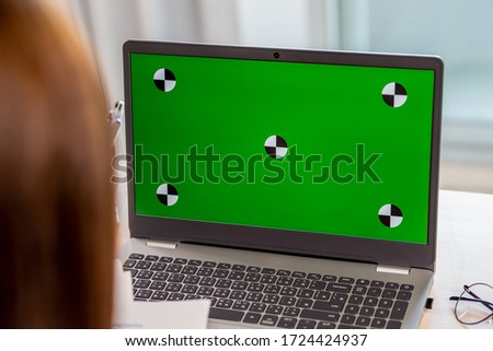 telework concept - Asian business woman use laptop with green chroma key screen to join a video meeting or remote work at home