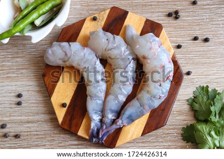 Cleaned, Peeled & Deveined Tiger Prawns or Asian tiger Shrimps. Also known as Kolambi or Bagda chingri. Recipe ingredients like pepper, chilies, garlic, curry leaves at background with copy space. 