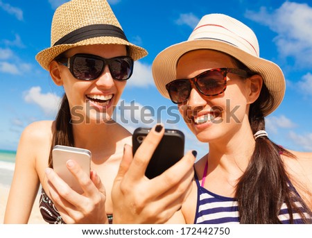 Summer holiday, technology and beach concept. Girls using smart phone on the beach.