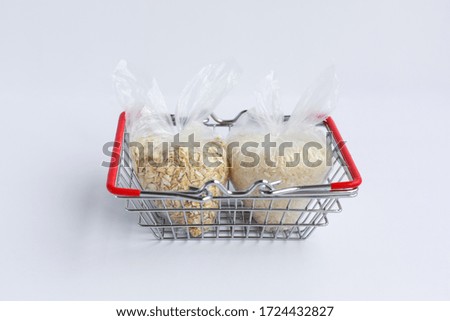 various groats in packages in a grocery basket on a white background. Rice and oatmeal