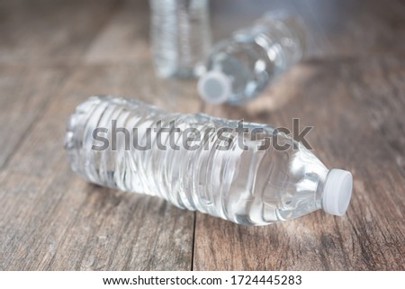 A view of three plastic water bottles with no label, on a wooden surface.