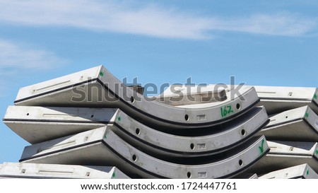 Curved pre cast concrete interlocking tunnel segments stacked. Blue sky background