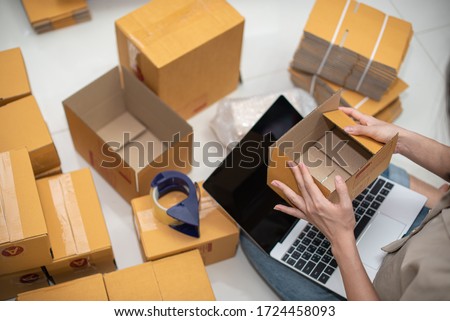 Female business owner working, packing the order for shipping to customer. Female entrepreneur packaging box for delivery. Royalty-Free Stock Photo #1724458093