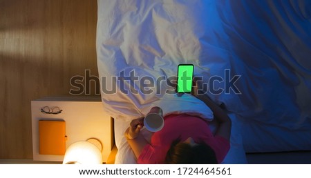top view of asian woman use smartphone with green screen on the bed in the room