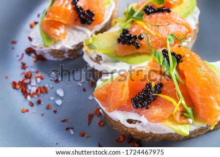 Closeup of fresh bruschetta avocado salmon and black caviar. Diet morning food background.